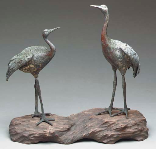 A PAIR OF BRONZE CRANES ON A GNARLED WOOD ROOT,