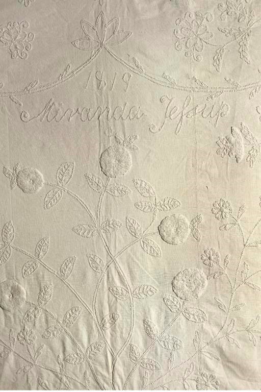 A whitework 'caddy' quilt, embroidered with a large urn of flowers beneath the inscription '1819, Miranda Jessop', the field cornered with thistles and roses, with plushwork flower-heads and an outer border of plushwork swags--84in. (214cm.) square, English; a shaped embroidered whitework coverlet centred with a dove with outstretched wings within a diamond lattice of stylised flowers, with some plushwork detail, 19th century; and a small composite linen cord quilted coverlet, possibly made up from petticoat panels--60 x 52in. (152 x 132cm.), 18th century