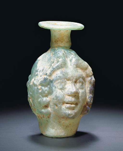 A ROMAN GREEN GLASS JANUS-HEAD SPRINKLER FLASK