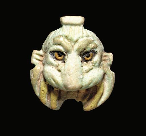 AN EGYPTIAN PALE GREEN FAIENCE LION MASK AMULET