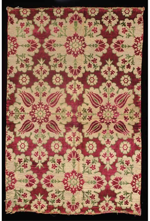 A fine velvet panel, woven with a crimson and sage green silk pile voided to a metal ground, with tulip and chrysanthemum medallions--38¼. x 25in. (97 x 63.5cm.), Ottoman, 17th century, some wear to metal thread