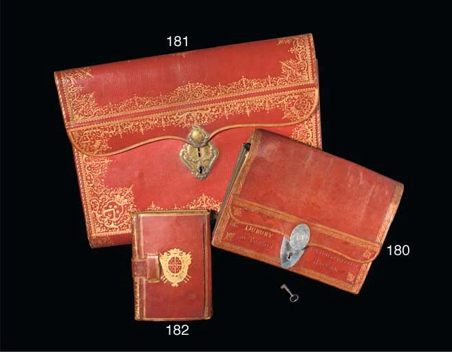 PORTEFEUILLE DU CONTRÔLEUR GÉNÉRAL DES FINANCES DE LOUIS XVI. (335 x 447 mm). Maroquin rouge dans le goût de Derome, large dentelle à l'oiseau (fers à l'oiseau de deux sortes) bordée de filets droits et dentés, le fond du portefeuille décoré comme un dos lisse à filets gras et maigres et large fleuron répété, doublure du rabat décorée d'une dentelle florale et libellules, l'extréméité du rabat à semé de fleurs tigées, doublure intérieure de soie bleu ciel, cordon de même (décousu à l'une des extrémités, complet), serrure à deux plaques de cuivre à décor repoussé, gravée aux armes de Louis Gabriel TABOUREAU DES RÉAUX (1718-1782, Olivier 337). (Fond partiellement décousu ou déchiré, quelques taches et égratignures, sans la clef.)