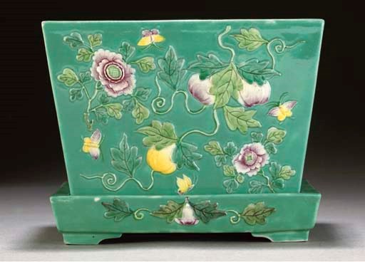 A famille rose green ground planter and stand, 20th century
moulded with butterflies amongst fruit and flower sprays, moulded Qianlong seal marks -- the planter 7½in. (19cm) long. 	 (2)