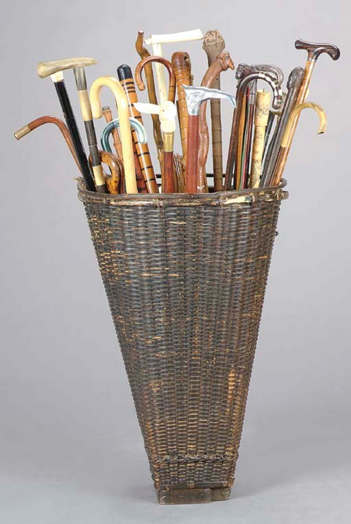 A COLLECTION OF WALKING STICKS AND UMBRELLAS IN A WOVEN BASKET,