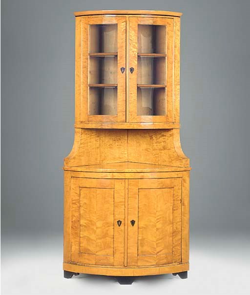 A GERMAN BIEDERMEIER SATIN BIRCH AND EBONISED BOWFRONT CORNER CUPBOARD