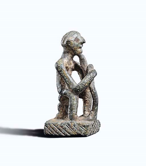A GEOMETRIC GREEK BRONZE SEATED MALE FIGURE