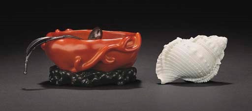 A CORAL-RED ENAMELLED BRUSHWASHER AND A CERAMIC CONCH SHELL