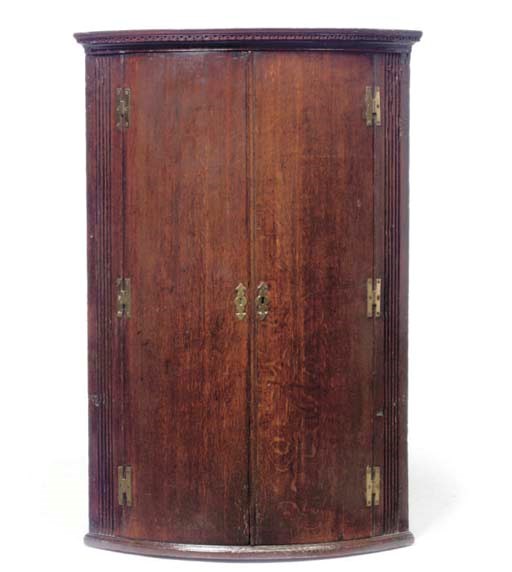 A GEORGE III OAK BOWFRONT CORNER CABINET