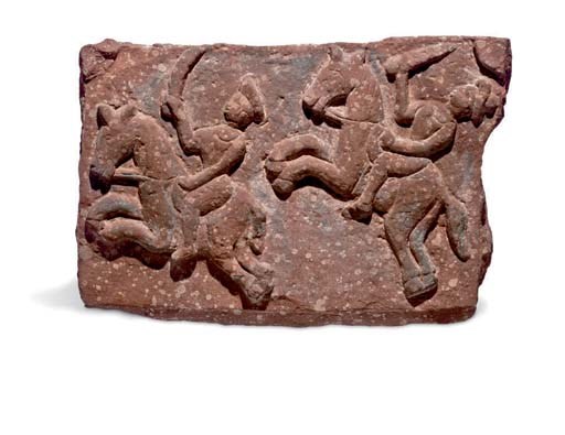 A mottled red sandstone relief with riders