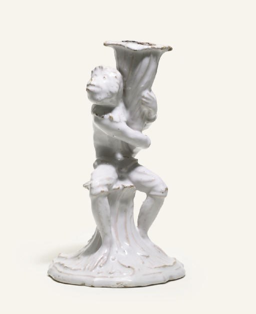 A GERMAN WHITE FAYENCE CANDLESTICK FIGURE