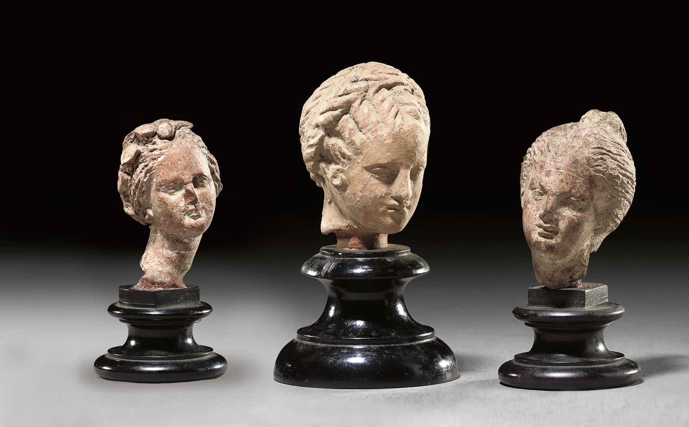 FOUR GREEK TERRACOTTA FEMALE HEADS
