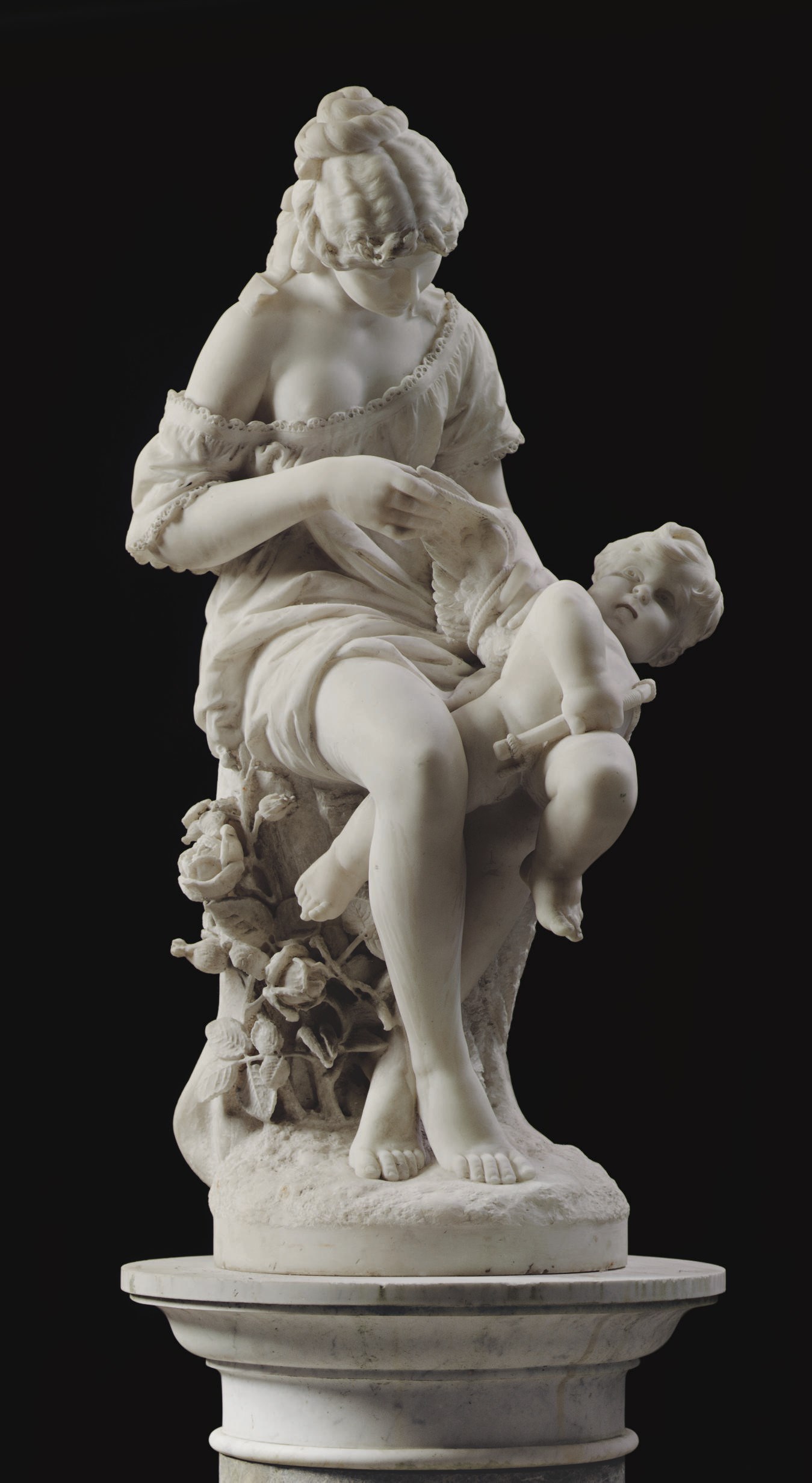 AN ITALIAN MARBLE FIGURAL GROUP ENTITLED 'THE PUNISHMENT OF CUPID', ON PEDESTAL