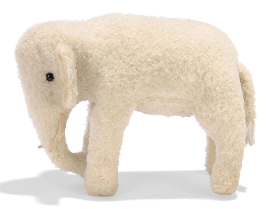 A STEIFF WOOL PLUSH STANDING ELEPHANT, (1514,0), white, black boot button eyes, felt tusks, velvet ear-linings, squeaker and FF button, circa 1912 --6½in. (16.5cm.) long (very minor wear)