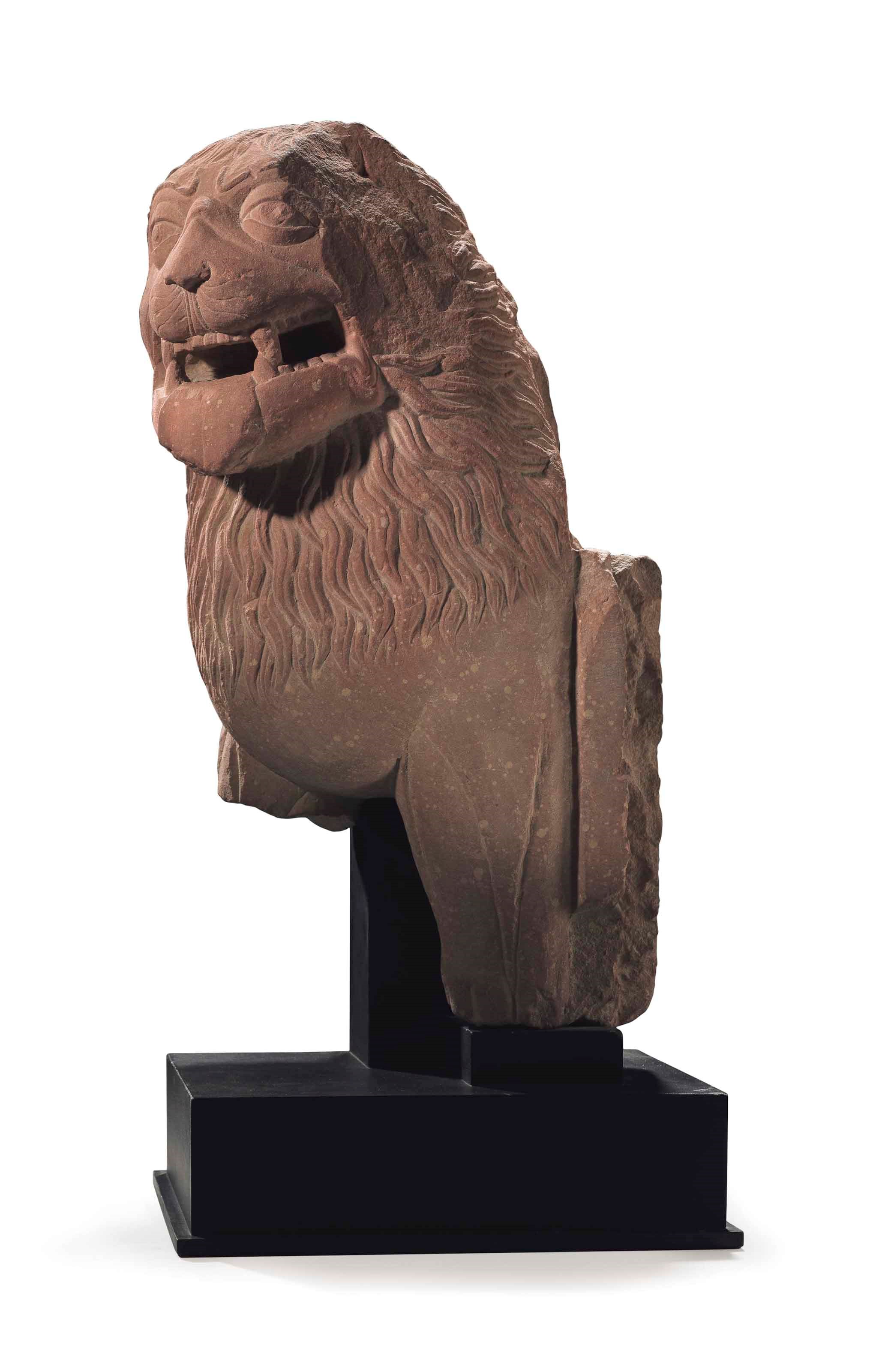 A mottled red sandstone figure of a lion