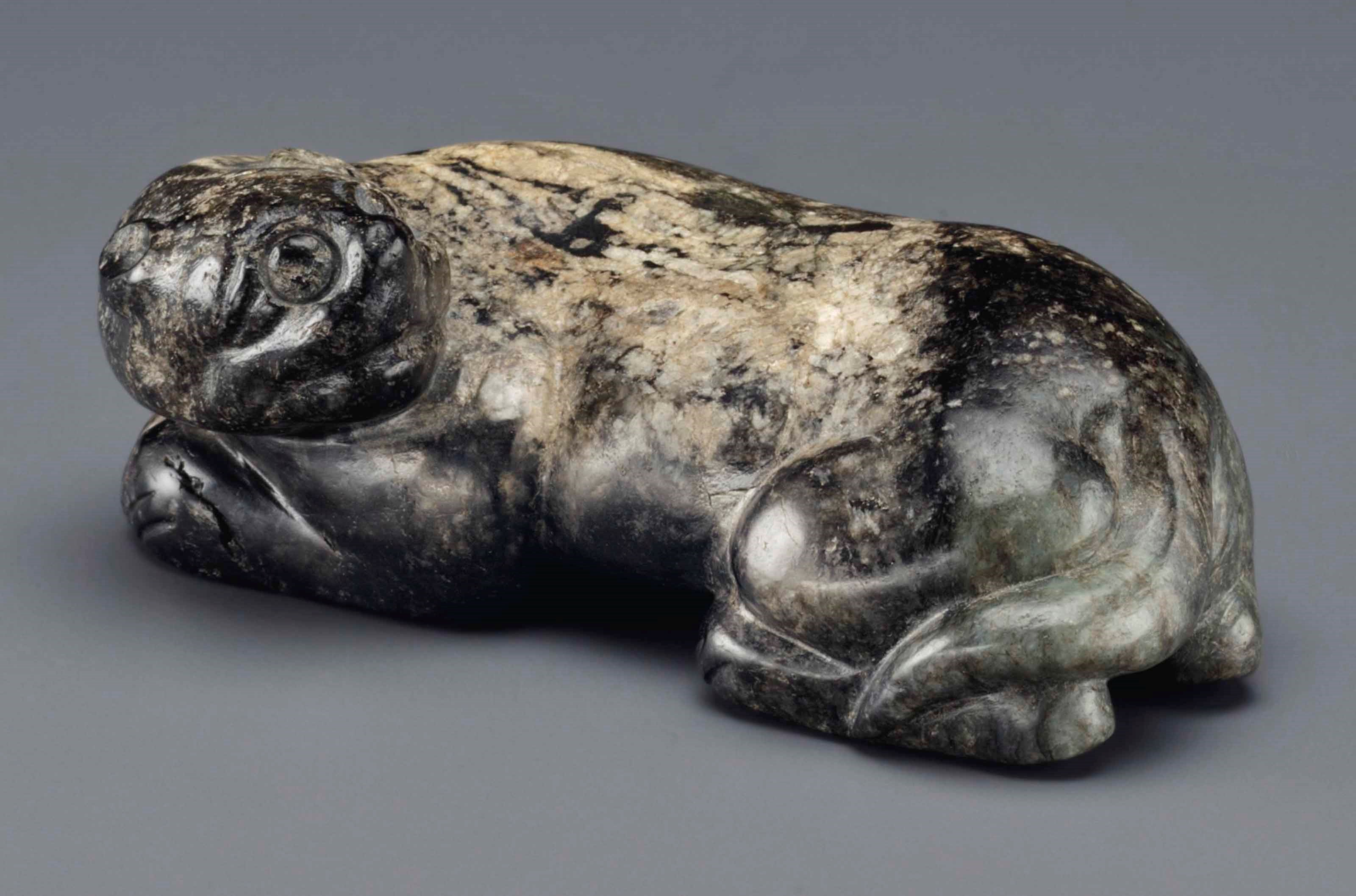 A BLACK AND BUFF OPAQUE JADE FIGURE OF A RECUMBENT TIGER