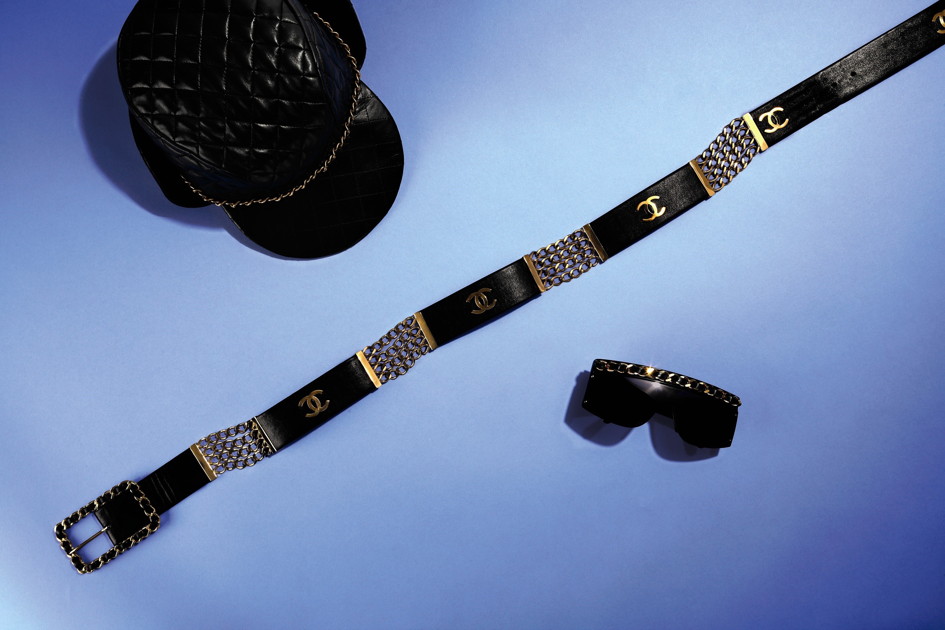 A SET OF THREE:A PAIR OF BLACK & GOLD CHAIN SUNGLASSESA BLACK & GOLD LEATHER CC CHAIN BELTA BLACK LAMBSKIN LEATHER QUILTED HAT
