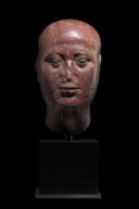 AN EGYPTIAN RED QUARTZITE HEAD OF A PRIEST