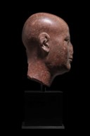 AN EGYPTIAN RED QUARTZITE HEAD OF A PRIEST