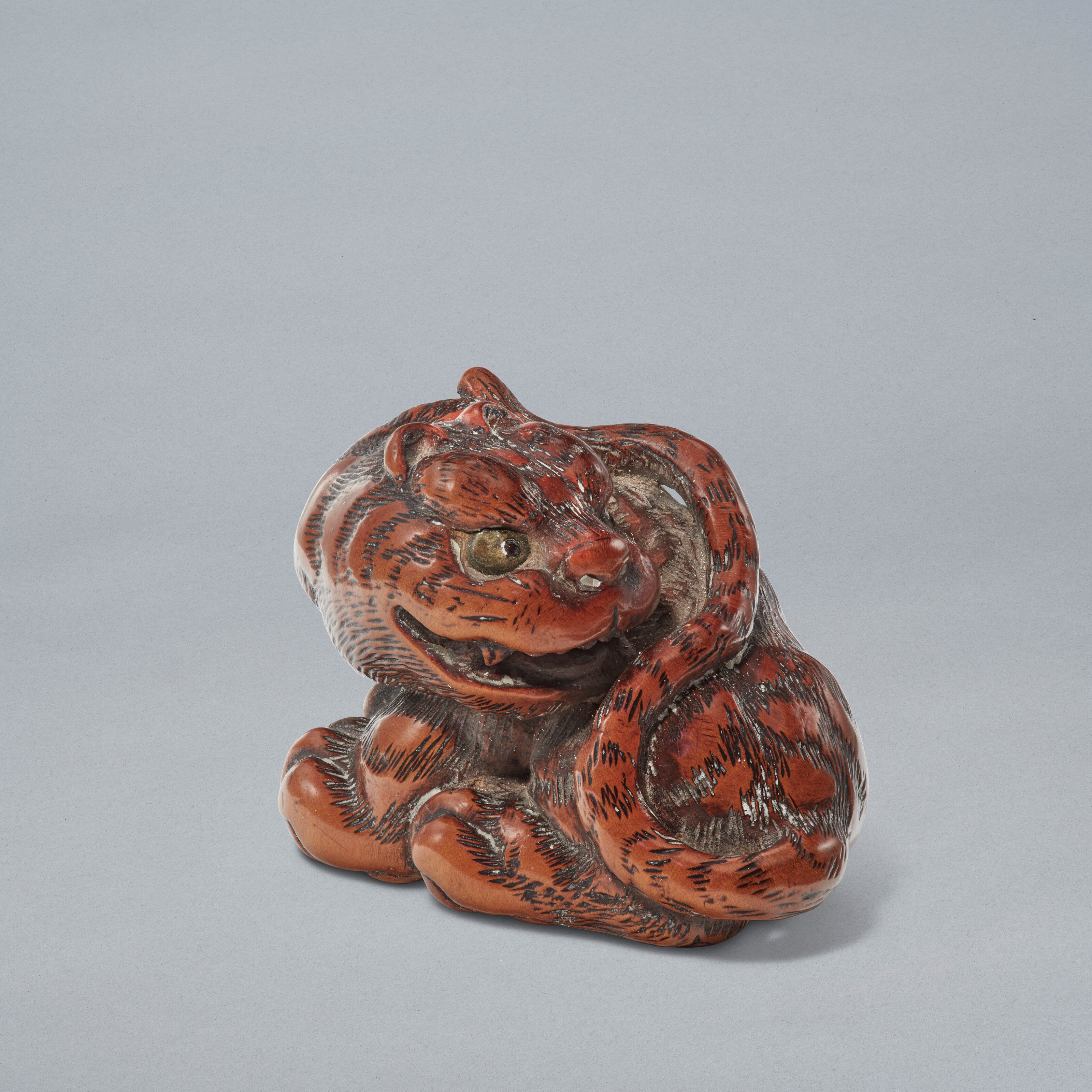 A CARVED WOOD NETSUKE OF A TIGER