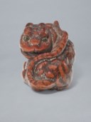 A CARVED WOOD NETSUKE OF A TIGER