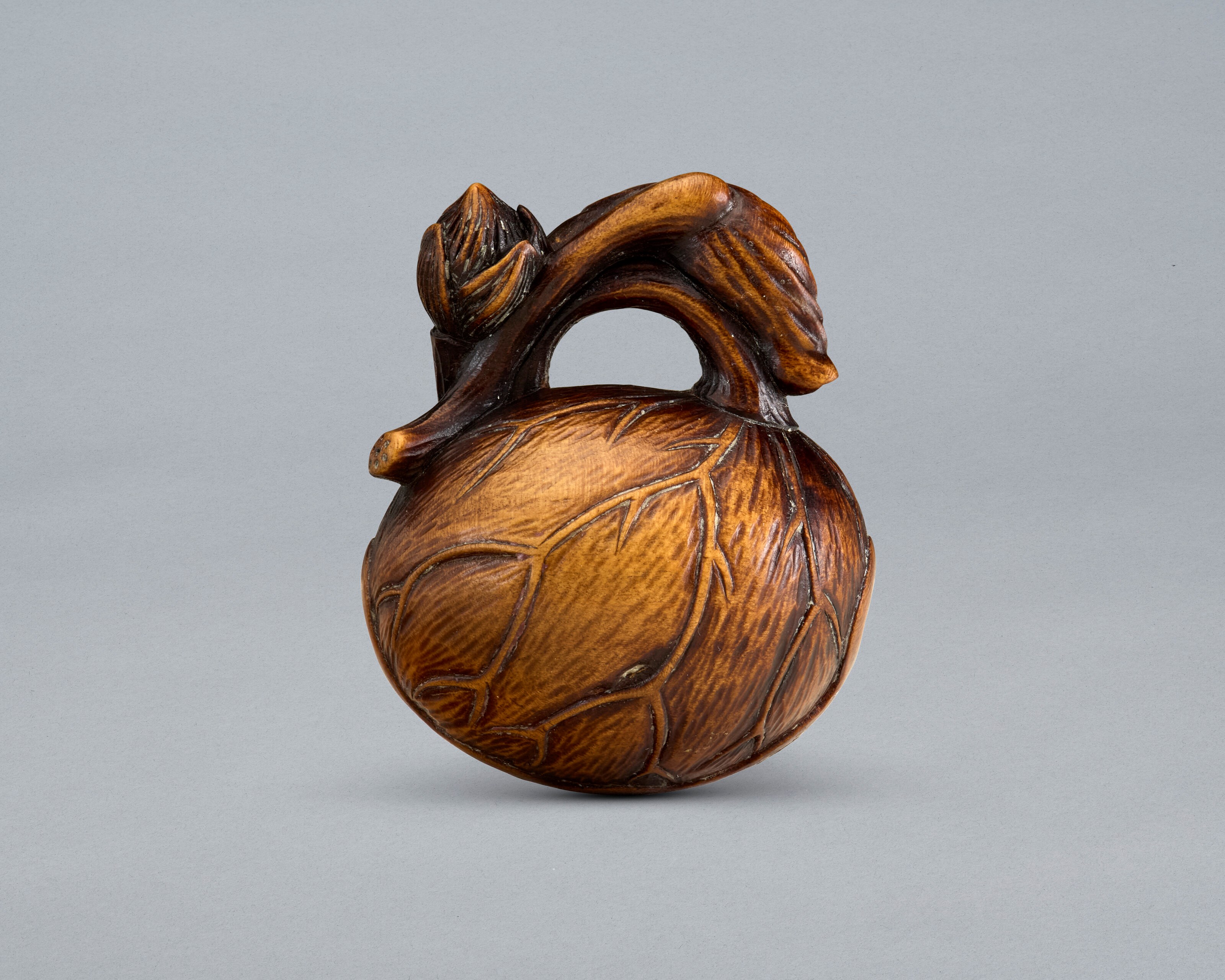 A CARVED WOOD NETSUKE OF LOTUS LEAVES FORMING A MOKUGYO