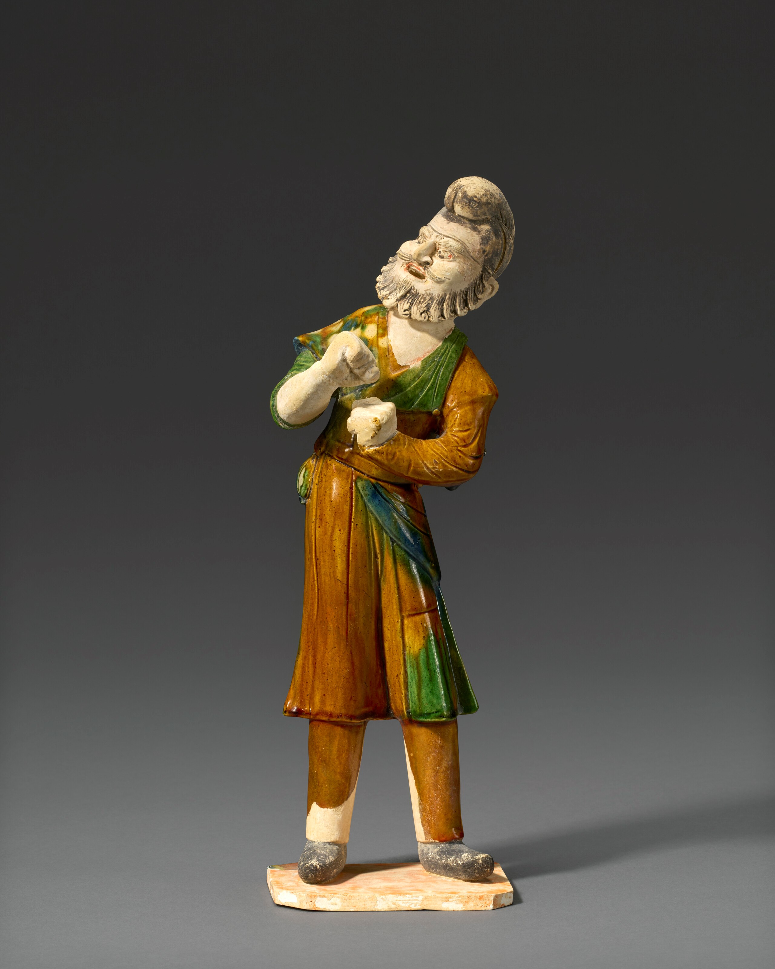 A SANCAI-GLAZED AND PAINTED POTTERY FIGURE OF A FOREIGN GROOM