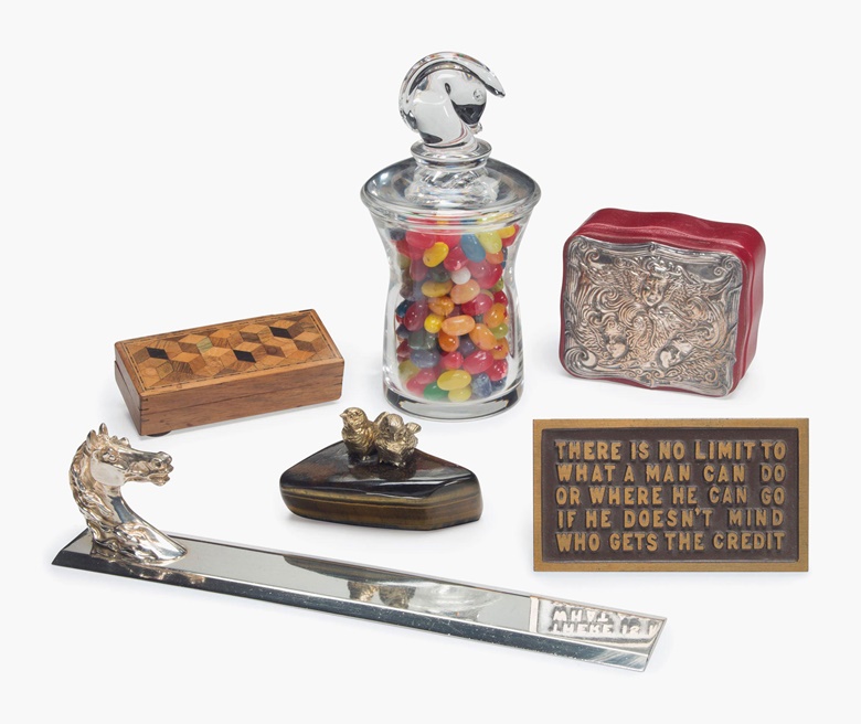 A group of desk accessories from the President’s desk, 20th century. Comprising a bronze plaque with the Reagan quotation,‘THERE IS NO LIMIT TO WHAT A MAN CAN DO OR WHERE HE CAN GO IF HE DOESN’T MIND WHO GETS THE CREDIT’; an Hermès silver blotter with horse head, marked to reverse; a glass jar with horse-head lid enclosing jelly beans; an English red leather and