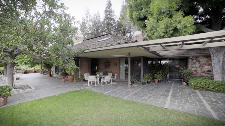Located at the top of a bougainvillea-lined driveway, the house is set in lush gardens with views of downtown Los Angeles and Century City