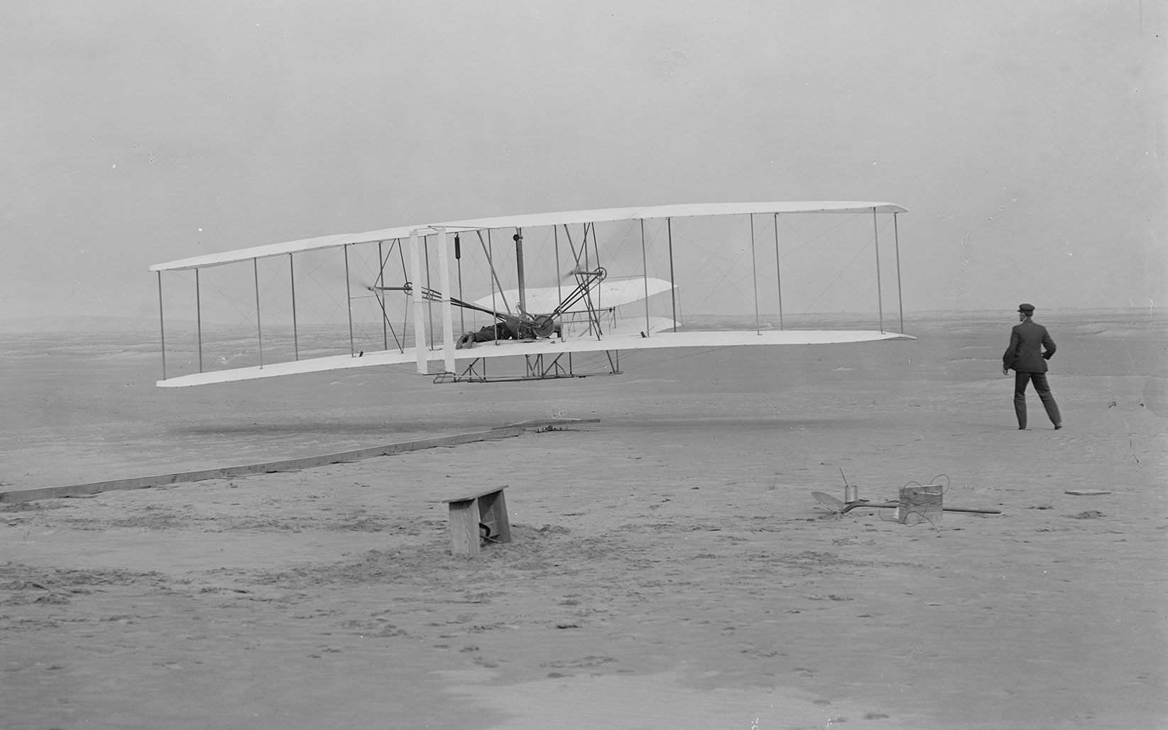 First flight — 120 feet in 12 seconds, 10.35am; Kitty Hawk, North Carolina, 17 December, 1903. Orville Wright at the controls; Wilbur Wright running alongside to balance the machine. Library of