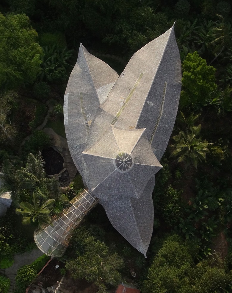 Sharma Springs, Green Village, Bali. Ibuku, 2012 From above, this building looks like dry petals on a bed of moss. It is in fact a six-storey forest home made entirely of bamboo. Each lanceolate leaf is a roof covering an open wing of the house; the thick grey stalk is a tunnel that crosses a green ravine and leads to the building’s fourth floor. Photograph © Errol Vaes