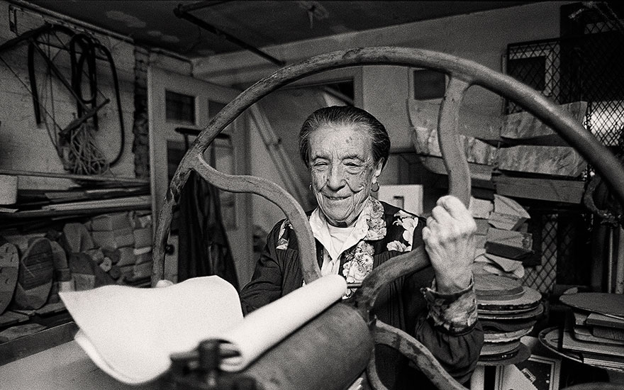 Louise Bourgeois at the printing press in the lower level of her home and studio on 20th Street, New York, 1995. Photograph by and © Mathias Johansson