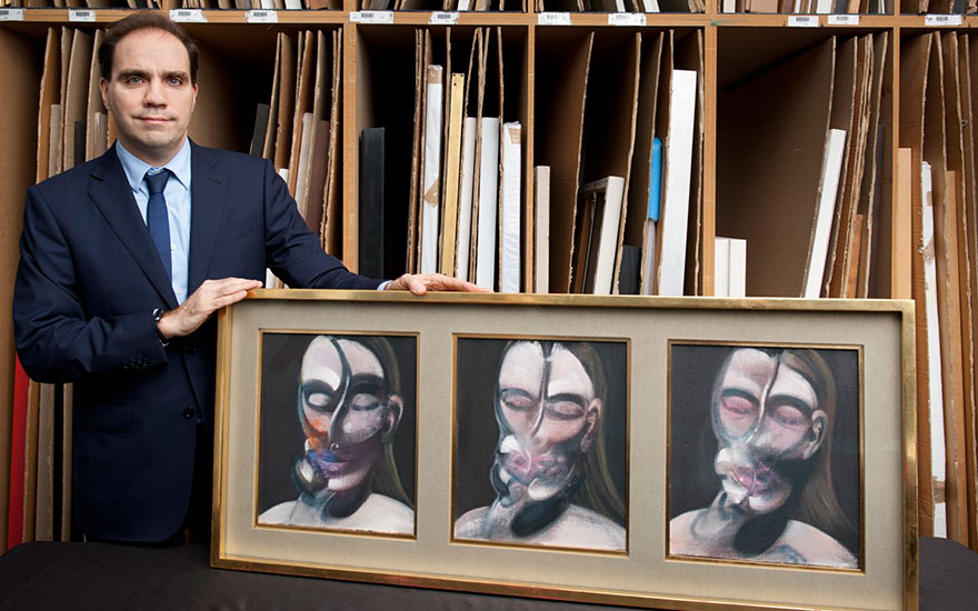 Francis Outred, Head of Post-War and Contemporary Art at Christie’s, with Francis Bacons Three Studies for a Portrait  (1976) © The Estate of Francis Bacon. All rights