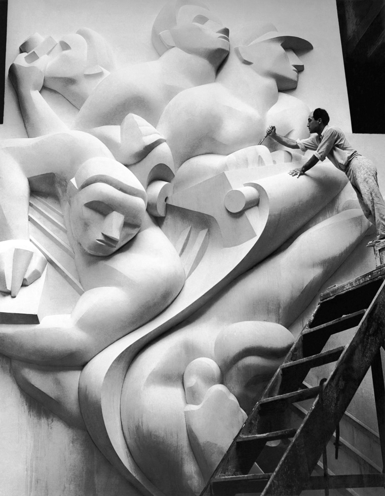 Isamu Noguchi working on the Associated Press Building plaque, which was carved in plaster and cast in stainless steel — then the largest-ever stainless-steel casting, 1940. Credit Underwood Archives Getty Images. Artwork © The Isamu Noguchi Foundation and Garden MuseumARS, New York and DACS, London 2018