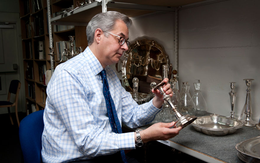 Harry Williams-Bulkeley examines a silver candlestick in a warehouse