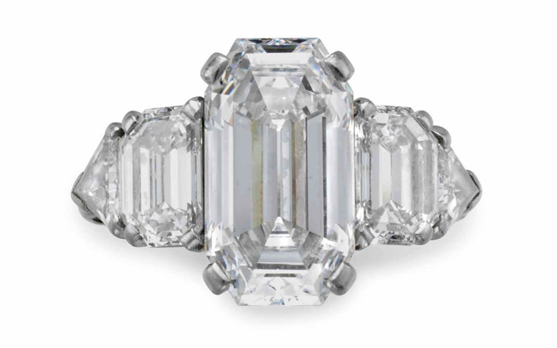In 1940 David Rockefeller purchased this ring set with a cut-cornered rectangular step-cut diamond, weighing approximately 5.63 carats, with epaulet and triangular-cut diamond shoulders, from Raymond Yard. He presented the ring to Peggy McGrath upon their engagement. In 1959 the ring was returned to Raymond Yard, who altered the design, integrating additional diamonds on either side of the centre