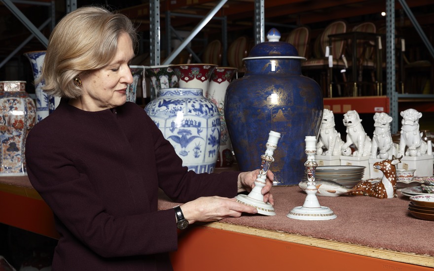 Specialist Becky MacGuire with a pair of Chinese export candlesticks with the arms of Philip V of Spain, circa 1725-30. 7¾ in (19.7 cm) high