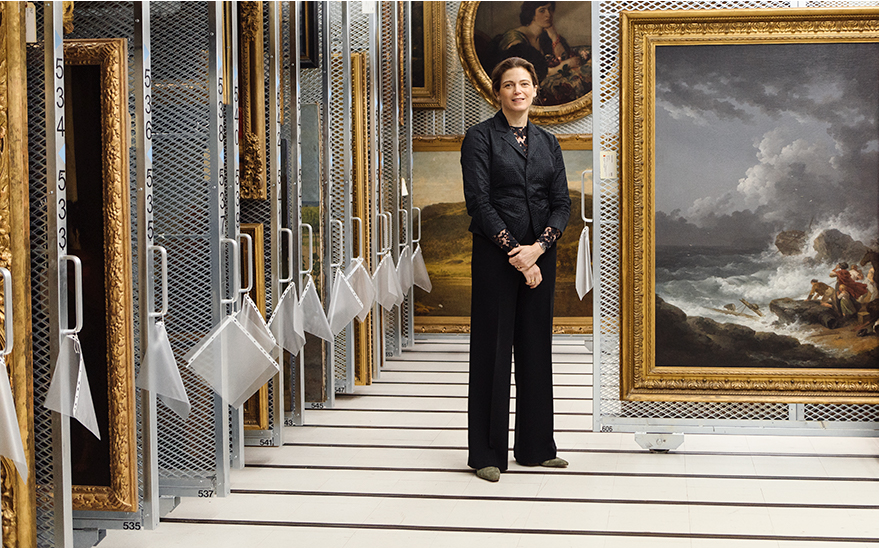 Sasha Suda, photographed in one of the vaults of the National Gallery of Canada, with George Morland, The Wreckers, c. 1790-1977 and, in the background, Charles Shannon, Lady in Black Furs, 1908.
