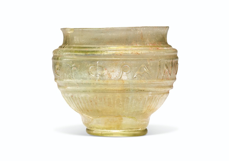 A Roman green glass beaker with inscription, circa mid 1st century AD. 3¼ in (8.2 cm) high. Sold for $6,250 on 12 October 2021 at Christie’s in New York