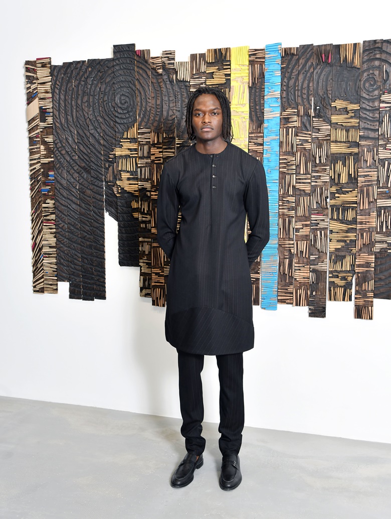 Kwame Mintah, co-founder and co-director of Efie Gallery, with El Anatsui’s Ancient Text, 2021. Photo Courtesy of Efie Gallery