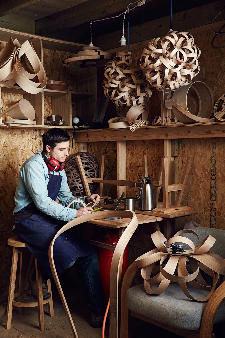 Steam-bent furniture maker Tom Raffield at his workshop in Cornwall, surrounded by prototypes. His furniture is created using wood from sustainably managed forests, while fabric comes from Abraham Moon & Sons in West Yorkshire, one of the last woollen mills in the UK. Photo courtesy of Tom Raffield and photographer Alun Callender