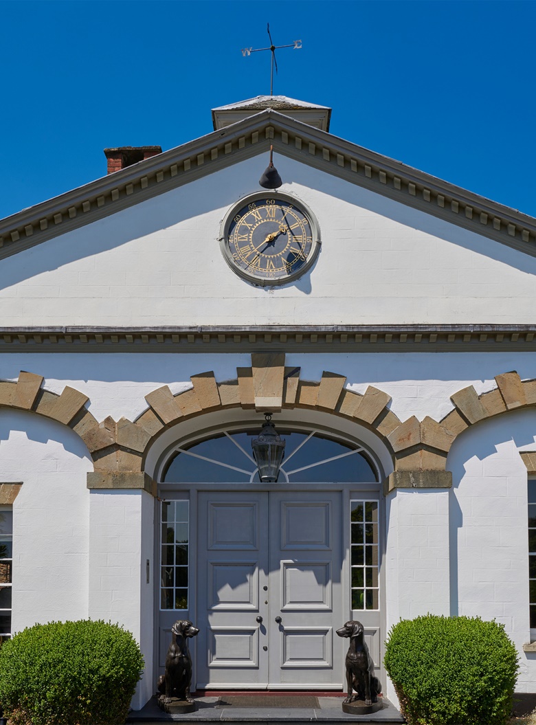 The entrance to the house, with a pair of patinated-bronze models of seated hounds, late 20th century. 39 in (99 cm) high. Estimate £4,000-6,000. Offered in An Opulent Aesthetic An Important Private Collection from an English Country House on 9 February 2023 at Christie’s in London