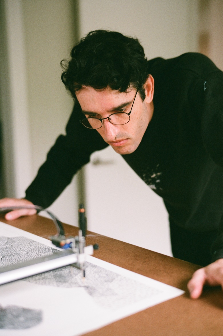 Tyler Hobbs working with a plotter, a programmable robot holding a pencil